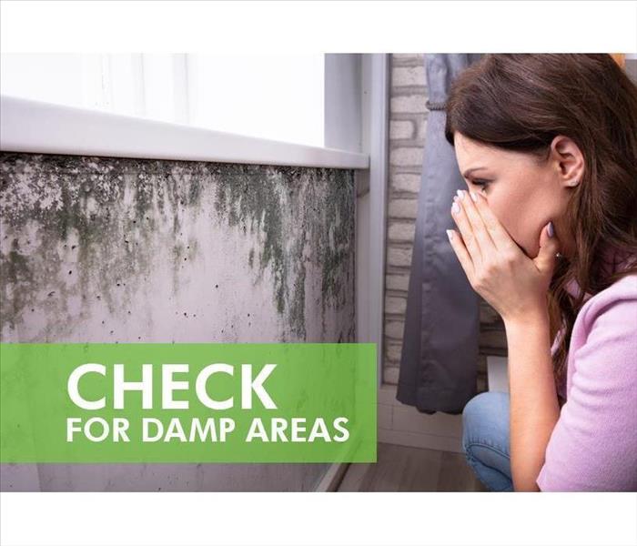 Woman covering her nose while staring at a wall covered with mold